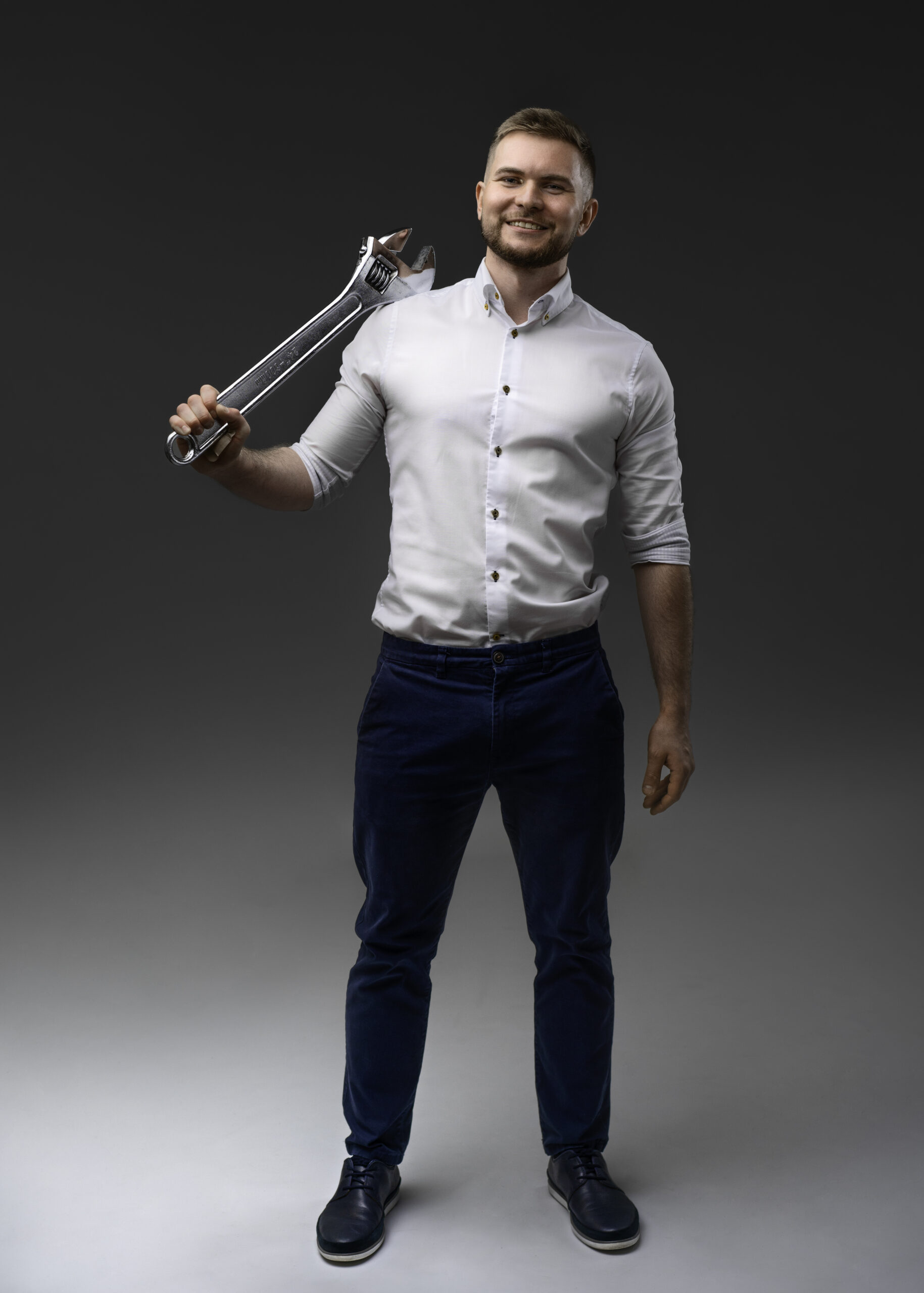 A man standing with a large wrench over his shoulder.